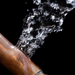 A bursting copper pipe in Plano, with water gushing out.