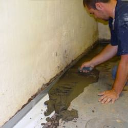 A basement waterproofer installing a perimeter drain system in Flower Mound