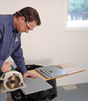 installing a waterproof vapor barrier on a basement floor to prepare for basement carpeting in a Plano home